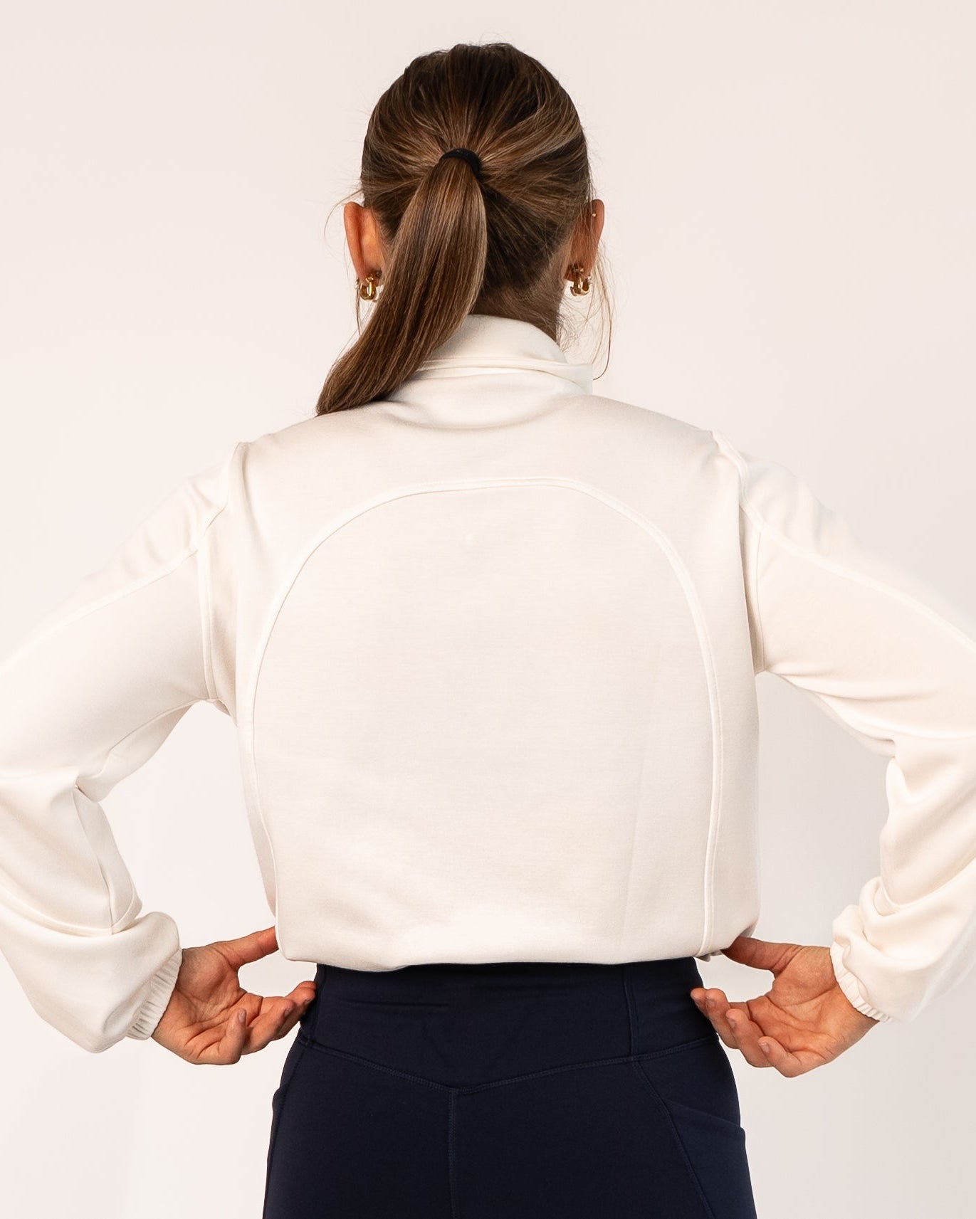 Person wearing a white blouse with a high collar on a plain background