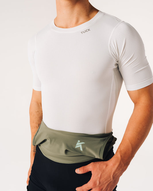 Person wearing a white t-shirt and green waist bag with a logo on a light gray background