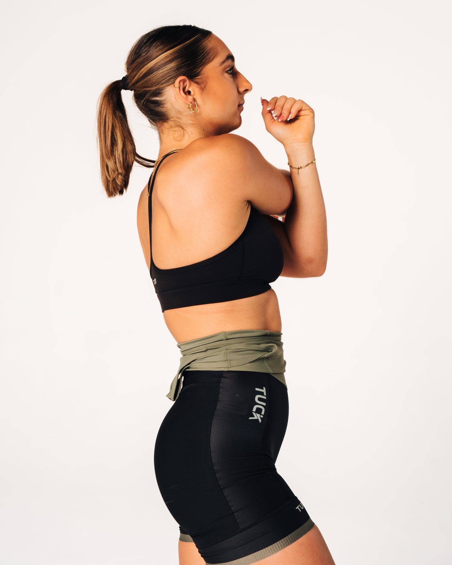 Woman wearing a black sports bra and black leggings with visible branding on a white background