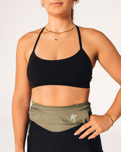 Person wearing a black sports bra and green athletic shorts with a visible brand logo.