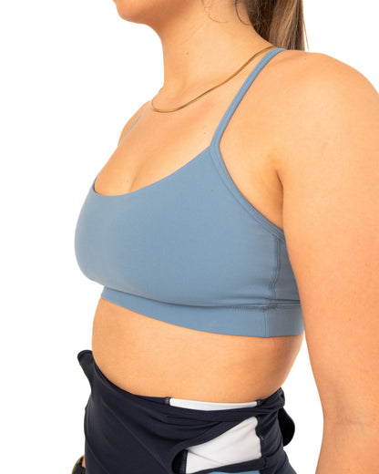 Woman wearing a blue sports bra and black shorts on a white background