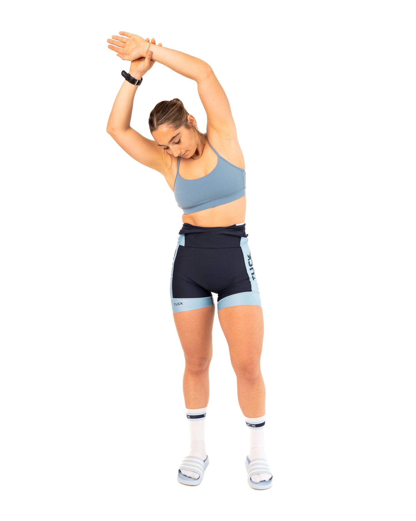Woman in athletic wear stretching on a white background