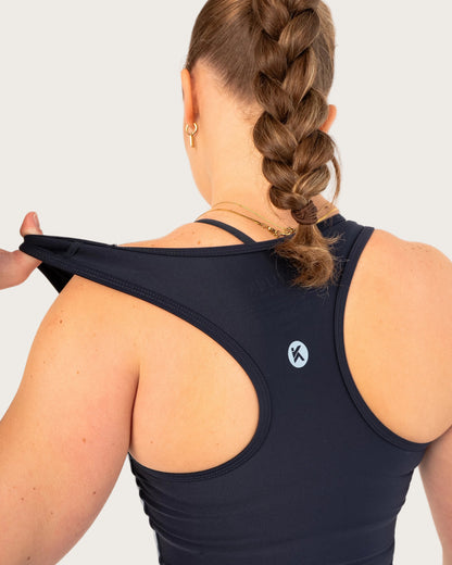 Person wearing a black sports bra with a visible brand logo on a white background