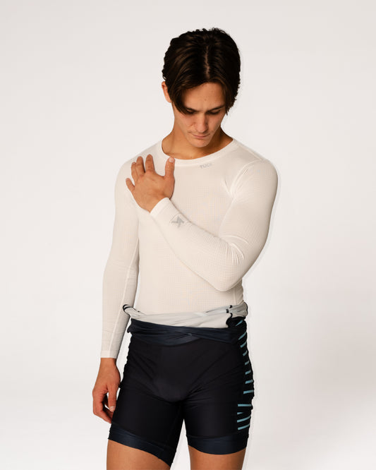 Person wearing a white long-sleeve shirt and black athletic shorts on a white background
